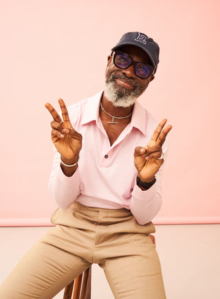 A man wearing a light pink polo shirt, khaki pants.